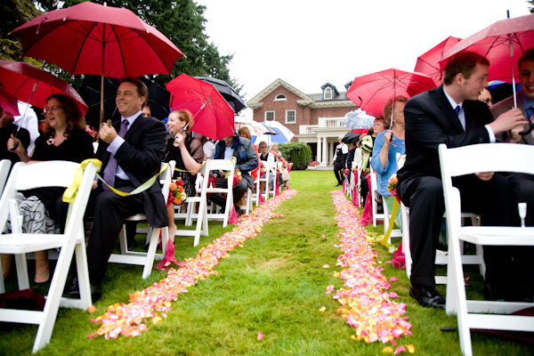 outdoor ceremony in the rain - guests all holding umbrellas - photo by Seattle based wedding photographers La Vie Photography